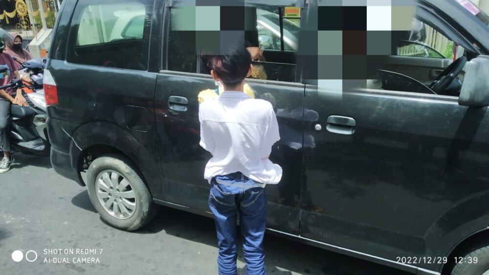 Salah seorang anak dibawah umur menawarkan dagangannya ke pengguna jalan disalah satu traffic light di Lombok Tengah.